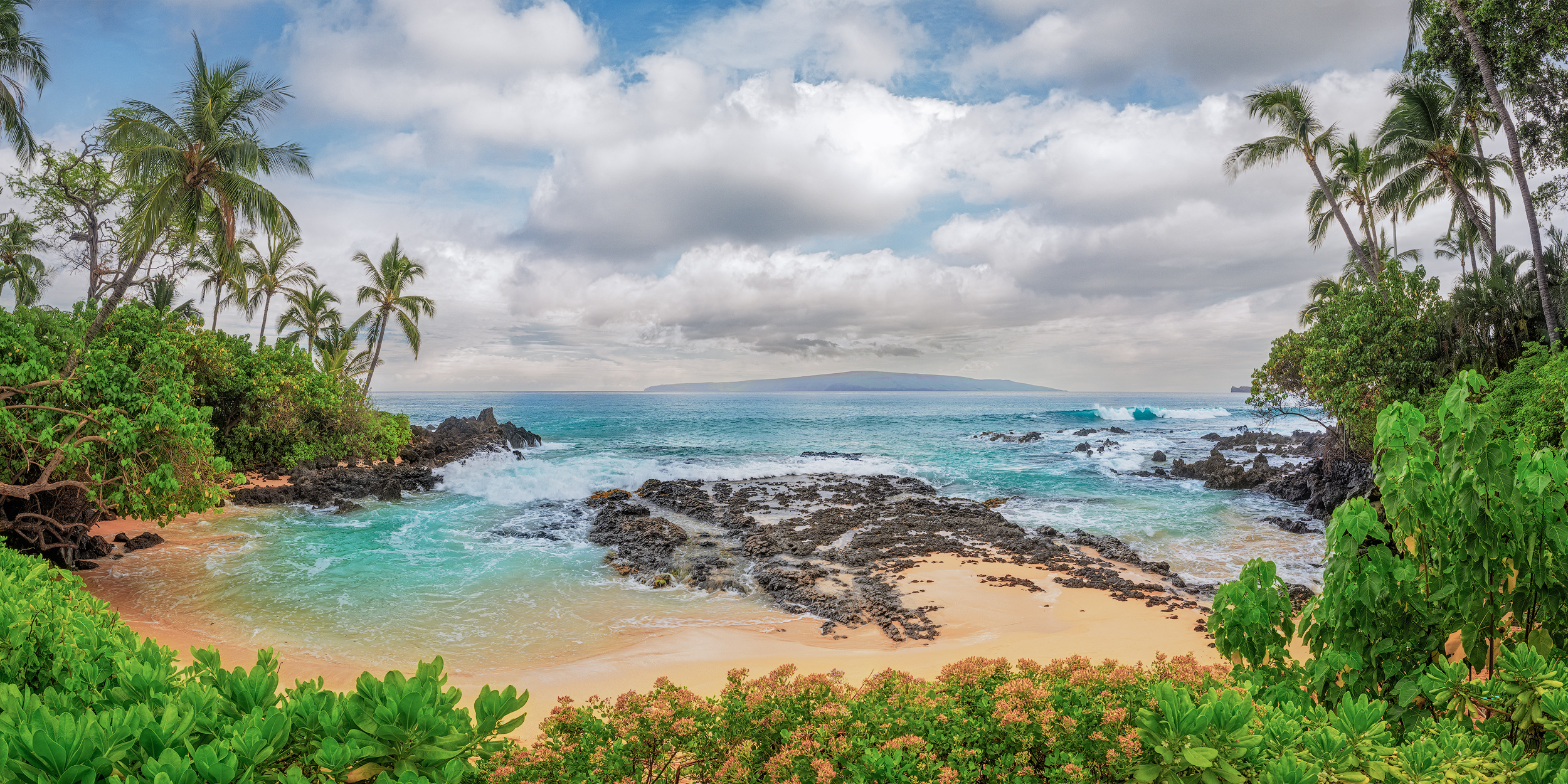 A Thousand Words Lush green plants and palm trees frame a secluded golden cove with turquoise waves and lava rocks at Secret Beach in Maui.
