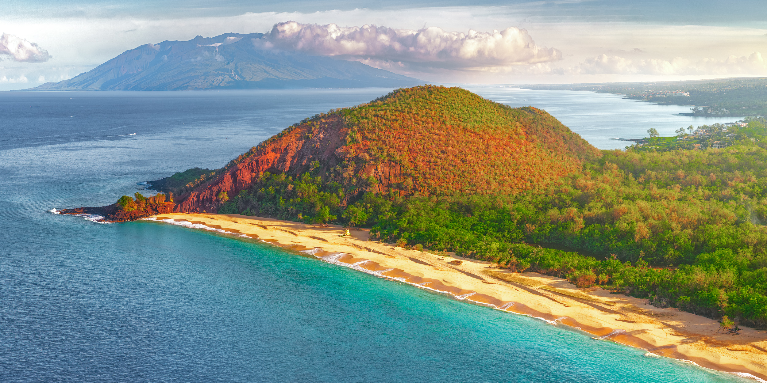 Ka ʻĀina o Mākena Early morning aerial view of Makena Big Beach in Maui, showing golden sand, turquoise water, and Puu Olai cinder cone.